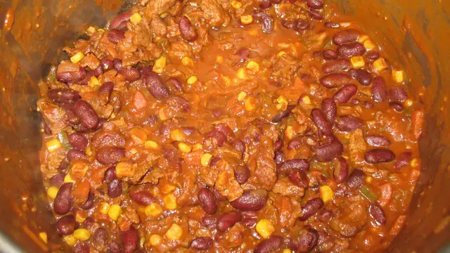 A pot of chili with kidney beans and corn simmering on the stove